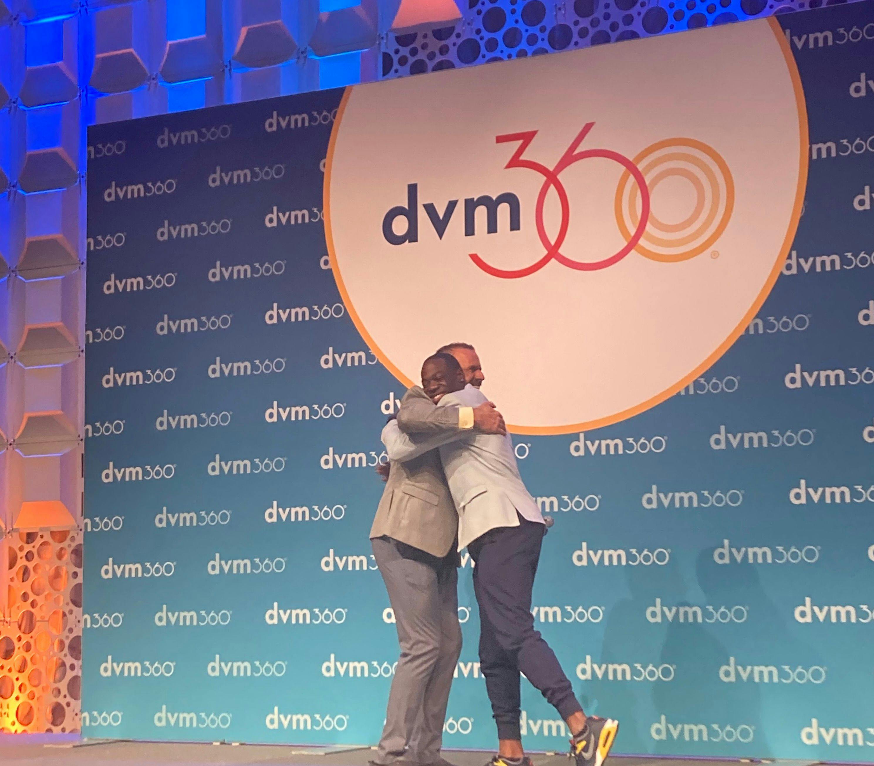 Walter Brown, BS, RVTg, VTS (ECC) (right) meets Adam Christman, DVM, MBA, dvm360® chief veterinary officer (left) in an embrace before delivering his keynote address.  